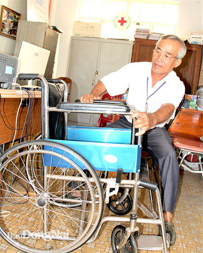 Ông Võ Văn Nga đang sửa lại chiếc xe lăn cũ để chuẩn bị trao cho một nạn nhân chất độc da cam/dioxin. Ảnh: V.Tuyên