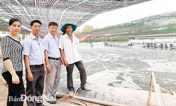 Ông Nguyễn Trường Đại (bìa phải) giới thiệu mô hình nuôi tôm công nghệ cao với cán bộ Hội Nông dân xã Vĩnh Thanh. Ảnh: Ban Mai