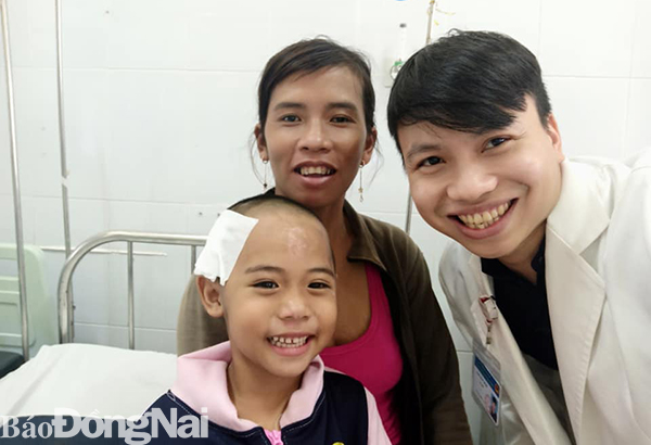 Bệnh nhi tươi cười chụp hình cùng mẹ và bác sĩ trước khi xuất viện