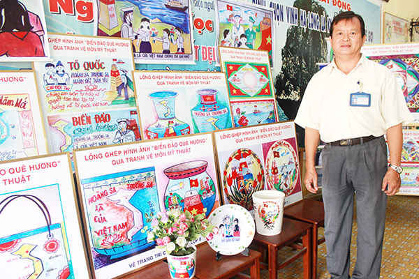 Thầy Trần Trung Hiền bên những bức tranh tự vẽ với chủ đề biển đảo quê hương. Ảnh: H.DUNG