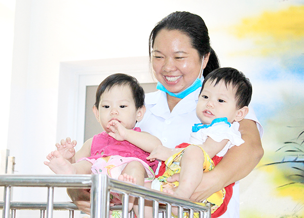 Chị Lưu Thị Lân, viên chức Trung tâm Công tác xã hội tỉnh - cơ sở 1 vui đùa với 2 trẻ sinh đôi tại trung tâm