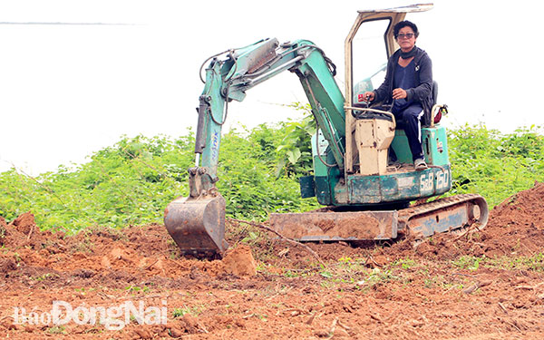 NSƯT Nguyễn Cao Minh trực tiếp lái máy xúc đất cải tạo một hòn đảo ở lòng hồ Trị An. Ảnh: Uyển Nhi