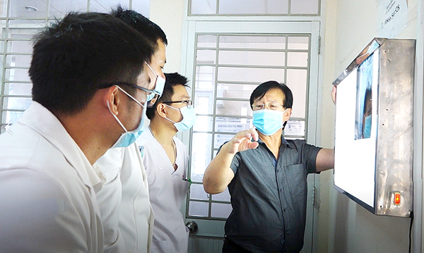GS-BS René D.Esser hướng dẫn các bác sĩ trẻ của Bệnh viện Đa khoa khu vực Long Khánh chẩn đoán trên phim chụp X-quang của bệnh nhân. Ảnh: Bích Nhàn