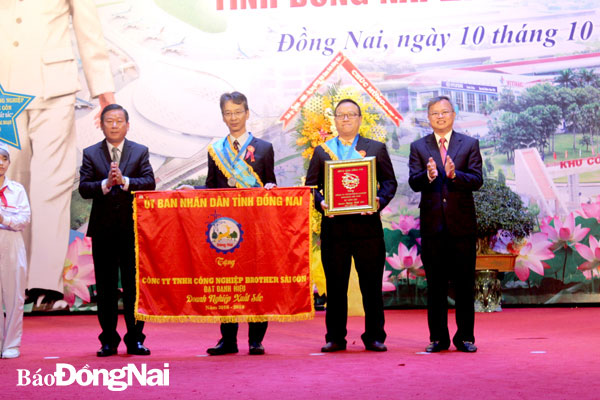 Chủ tịch UBND tỉnh Cao Tiến Dũng (bìa phải) và Trưởng ban Dân vận Tỉnh uỷ Đào Văn Phước (bìa trái) trao cờ cho doanh nghiệp xuất sắc trên địa bàn tỉnh. Ảnh: Nga Sơn