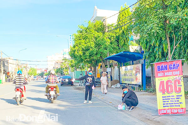 Một nhóm người phát tờ rơi ngay dưới lòng đường, trước khu vực nhà chờ xe buýt trên đường Cách Mạng Tháng Tám (TP.Biên Hòa). Ảnh chụp ngày 16-12-2020. (Ảnh: Trần Thanh Trúc)