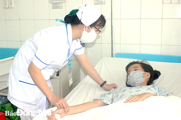 Điều dưỡng Lê Thị Kiều Trinh chăm sóc, trò chuyện với một bệnh nhân được điều trị tại khoa. Ảnh: Hạnh Dung