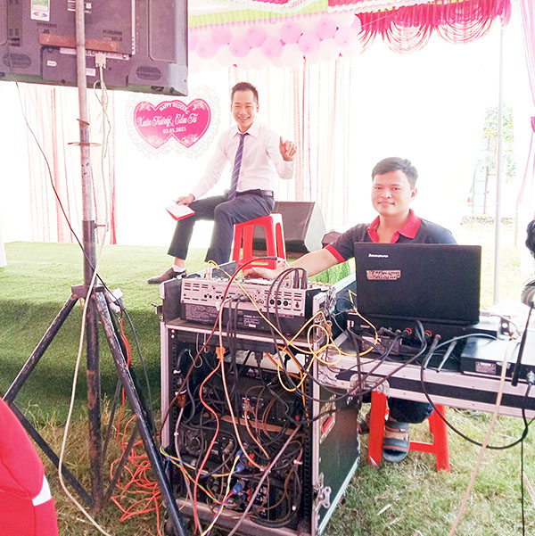 Anh Phan Duy Quý (phải) phục vụ âm thanh, ánh sáng cho một đám tiệc dịp cuối năm. Ảnh: T.Lâm