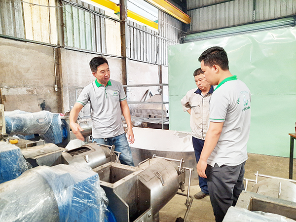 Ông Mai Thành Long (bìa trái) kiểm tra một hệ thống xử lý chất thải hữu cơ trước khi xuất xưởng. Ảnh: V.Thế