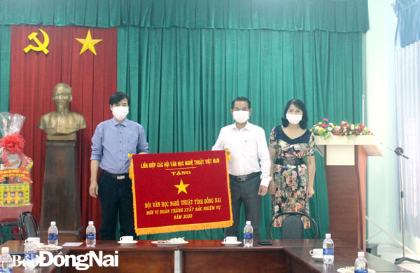 Phó chủ tịch UBND tỉnh Thái Bảo trao cờ thi đua xuất sắc năm 2020 của Liên hiệp các Hội Văn học nghệ thuật Việt Nam cho Hội Văn học nghệ thuật Đồng Nai. Ảnh: Ly Na