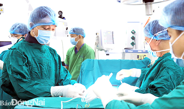BS Nguyễn Đăng Minh (bìa trái) chuẩn bị thực hiện ca phẫu thuật cột sống bằng phương pháp xâm lấn tối thiểu ghép TLIF bắt vít qua da. Ảnh: H.Dung