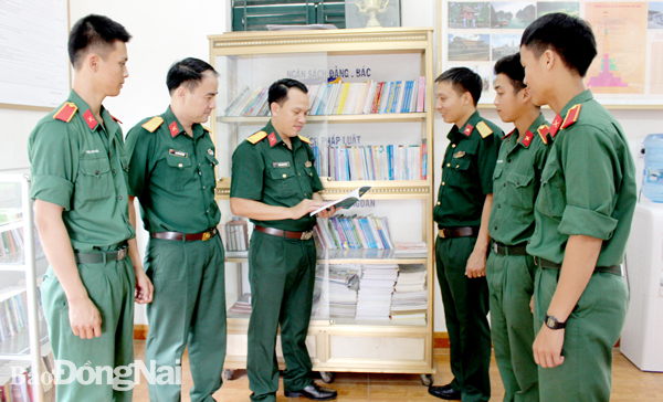 Thiếu tá Ninh Quang Thảo (thứ ba từ trái sang) giới thiệu tủ sách truyền thống cho tuổi trẻ đơn vị. Ảnh: N.Anh