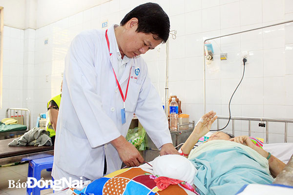 BS Nguyễn Tường Quang, Trưởng khoa Ngoại - chấn thương chỉnh hình, bỏng Bệnh viện Đa khoa Thống Nhất thăm khám cho bà L. sáng 13-4. ảnh: H.Dung
