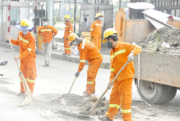 Công nhân dọn dẹp đất, đá tại quốc lộ 1K (TP.Biên Hòa). Ảnh: Võ Nguyên