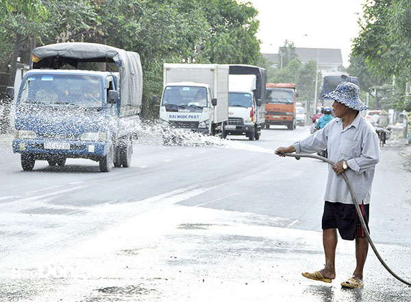 Người dân P.Tân Hạnh (TP.Biên Hòa) thường xuyên xịt nước trên bề mặt đường Bùi Hữu Nghĩa để giảm khói bụi khi xe cộ qua lại đông đúc mỗi ngày. Ảnh: Võ Nguyên