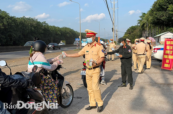 Lực lượng cảnh sát giao thông, cảnh sát cơ động tham gia phát nước, khẩu trang cho người dân trên quốc lộ 20