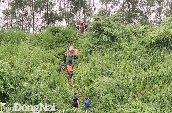 Hình lực lượng cứu hộ và người dân đưa thi thể hai học sinh lên bờ từ dưới sông Buông
