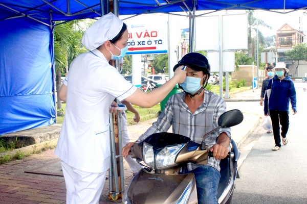 Nhân viên y tế đo thân nhiệt cho tất cả người vào Bệnh viện Đa khoa Đồng Nai. Ảnh: Hạnh Dung