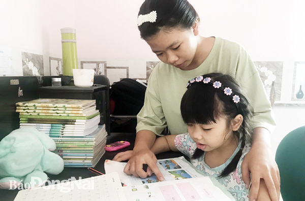 Bé Nguyễn Phạm Tường Vi (ngụ KP.3, P.Trảng Dài, TP.Biên Hòa) đang được chị dạy cho làm quen với môn Tiếng Việt