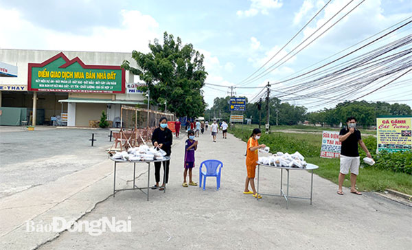 Người dân tại khu phong tỏa thuộc H.Nhơn Trạch được hỗ trợ cơm từ các tổ chức thiện nguyện. Ảnh: Tố Tâm