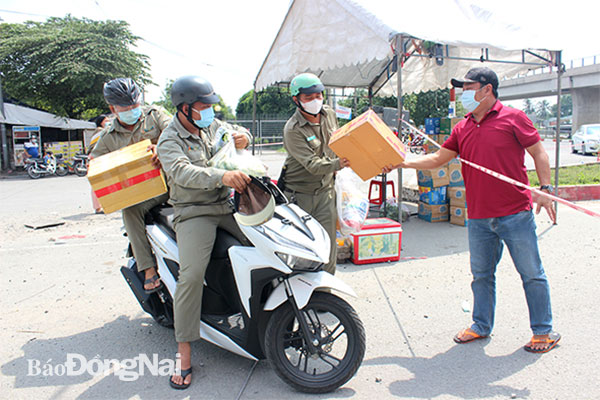 Lực lượng bảo vệ dân phố P.Tân Hạnh hỗ trợ vận chuyển thực phẩm từ chốt kiểm soát vào nhà một người dân. Ảnh: Trần Danh