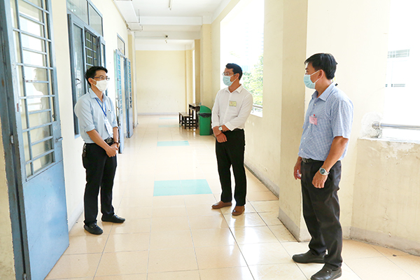 Phó giám đốc Sở GD-ĐT Đỗ Huy Khánh (bìa trái) trao đổi với lực lượng thanh tra thi giám sát bên ngoài hành lang các phòng chấm thi.
