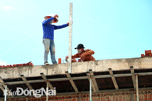 Thợ xây dựng đang căn chỉnh để hoàn thiện phần mái nhà cho một hộ dân