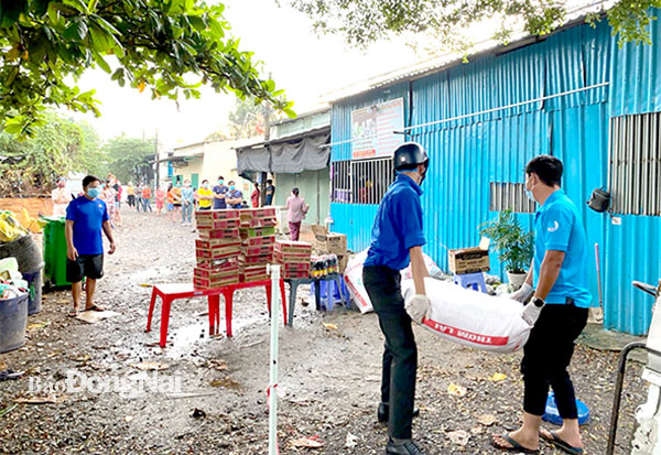 Anh Đào Minh Tuấn (bên phải) trao rau củ quả cho người dân khu vực phong tỏa. Ảnh: NVCC