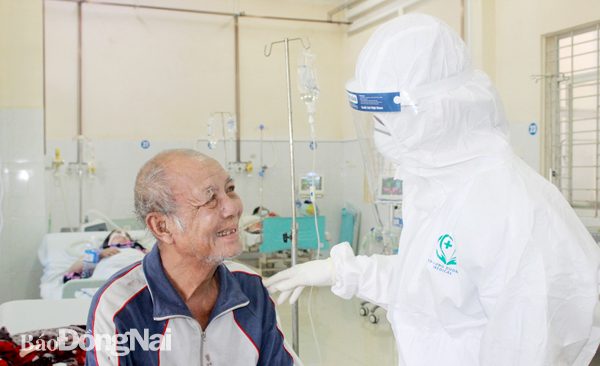 Điều dưỡng Nguyễn Thị Thùy Vân, Bệnh viện Đa khoa khu vực Long Khánh ân cần trò chuyện cùng bệnh nhân Covid-19 nặng sau một thời gian điều trị đã hồi phục tốt