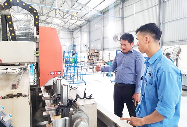 Anh Đinh Đức Điền (trái) kiểm tra một công đoạn sản xuất của doanh nghiệp. Ảnh: V.Gia
