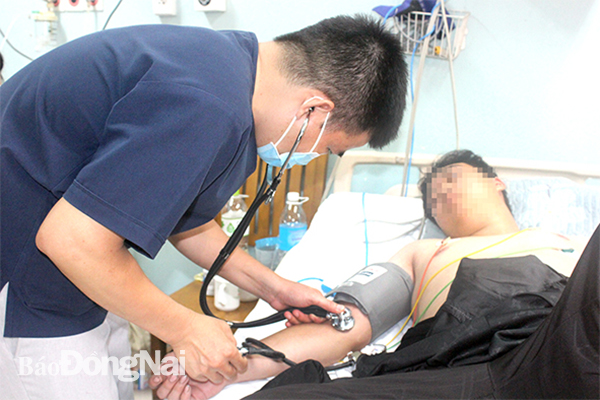 Bác sĩ kiểm tra sức khỏe cho một bệnh nhân bị sốc sốt xuất huyết đang điều trị tại Bệnh viện Đa khoa Đồng Nai