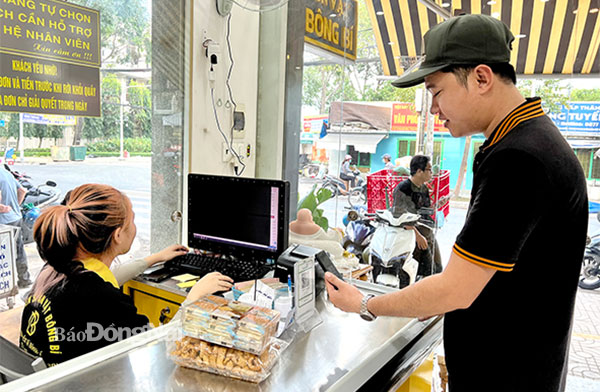 Khách hàng quét mã QR để thanh toán tại một cửa hàng bán đồ ăn vặt trên đường Phan Đình Phùng (TP.Biên Hòa). Ảnh: Hải Hà