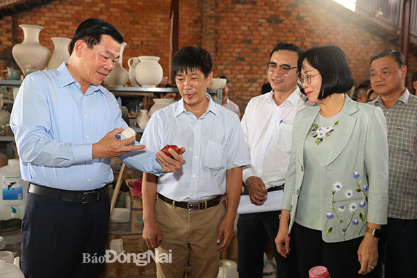 Lãnh đạo tỉnh trao đổi với chủ một doanh nghiệp sản xuất gốm ở TP.Biên Hòa về việc nâng cao chất lượng, đa dạng mẫu mã cho sản phẩm gốm địa phương. Ảnh: Huy Anh