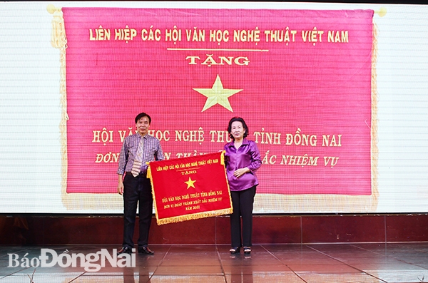 Bà Đặng Thị Phượng, Ủy viên Liên hiệp các Hội Văn học nghệ thuật Việt Nam trao cờ thi đua xuất sắc năm 2021 của Liên hiệp Hội cho Hội Văn học nghệ thuật Đồng Nai