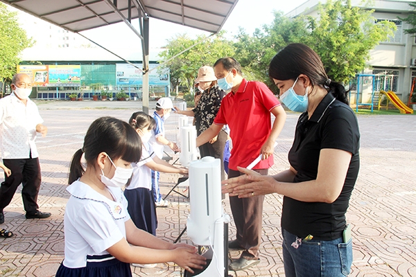 Tại cổng Trường tiểu học Lê Văn Tám, nhà trường đã bố trí giáo viên, hướng dẫn các em thực hiện khử khuẩn, đo thân nhiệt bằng máy tự động