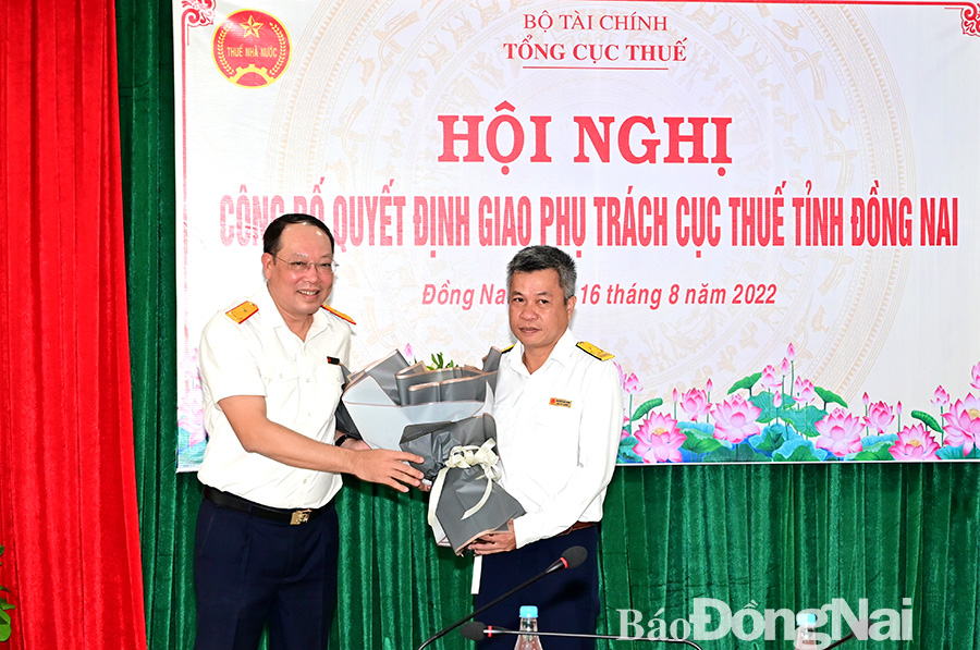  Phó tổng cục trưởng Tổng Cục thuế Vũ Xuân Bách (trái) tặng hoa chúc mừng ông Nguyễn Toàn Thắng.
