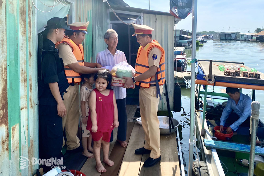 Trung tá Nguyễn Thế Thuận, Phó trưởng phòng Cảnh sát giao thông Công an tỉnh trực tiếp tặng quà cho người dân làng bè trên sông Đồng Nai (TP.Biên Hòa). Ảnh: CTV
