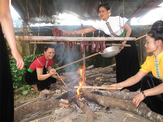 Thiếu nữ dân tộc Thái đang chuẩn bị món thịt hun khói. Ảnh: LƯU HỌC