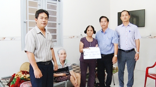 Thầy Phạm Như Ý (bìa phải) trao quà cho một gia đình có người bị bệnh hiểm nghèo tại xã Gia Kiệm