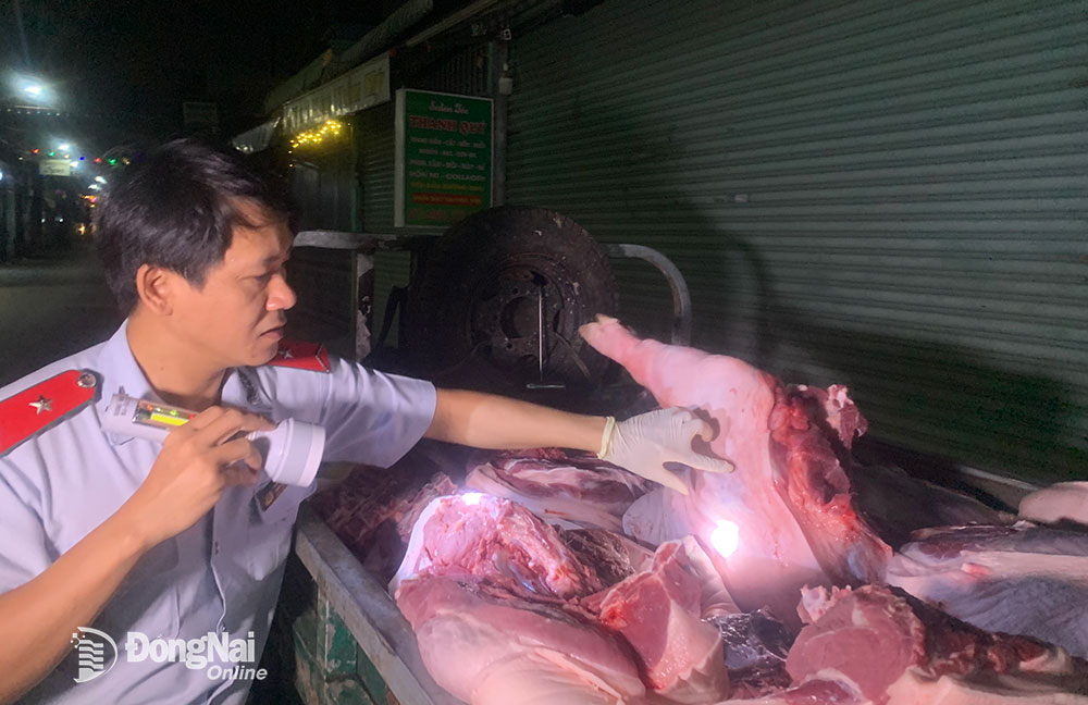 Cán bộ Chi cục Chăn nuôi - thú y Đồng Nai kiểm tra mộc thú y trên sản phẩm thịt heo tại chợ Tam Hòa (TP.Biên Hòa). Ảnh: B.Nguyên
