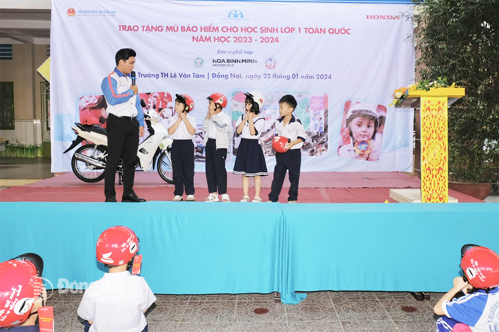 Đại diện Công ty CP Xe máy Hòa Bình Minh hướng dẫn các em học sinh đội mũ báo hiểm đúng cách. Ảnh: Đăng Tùng