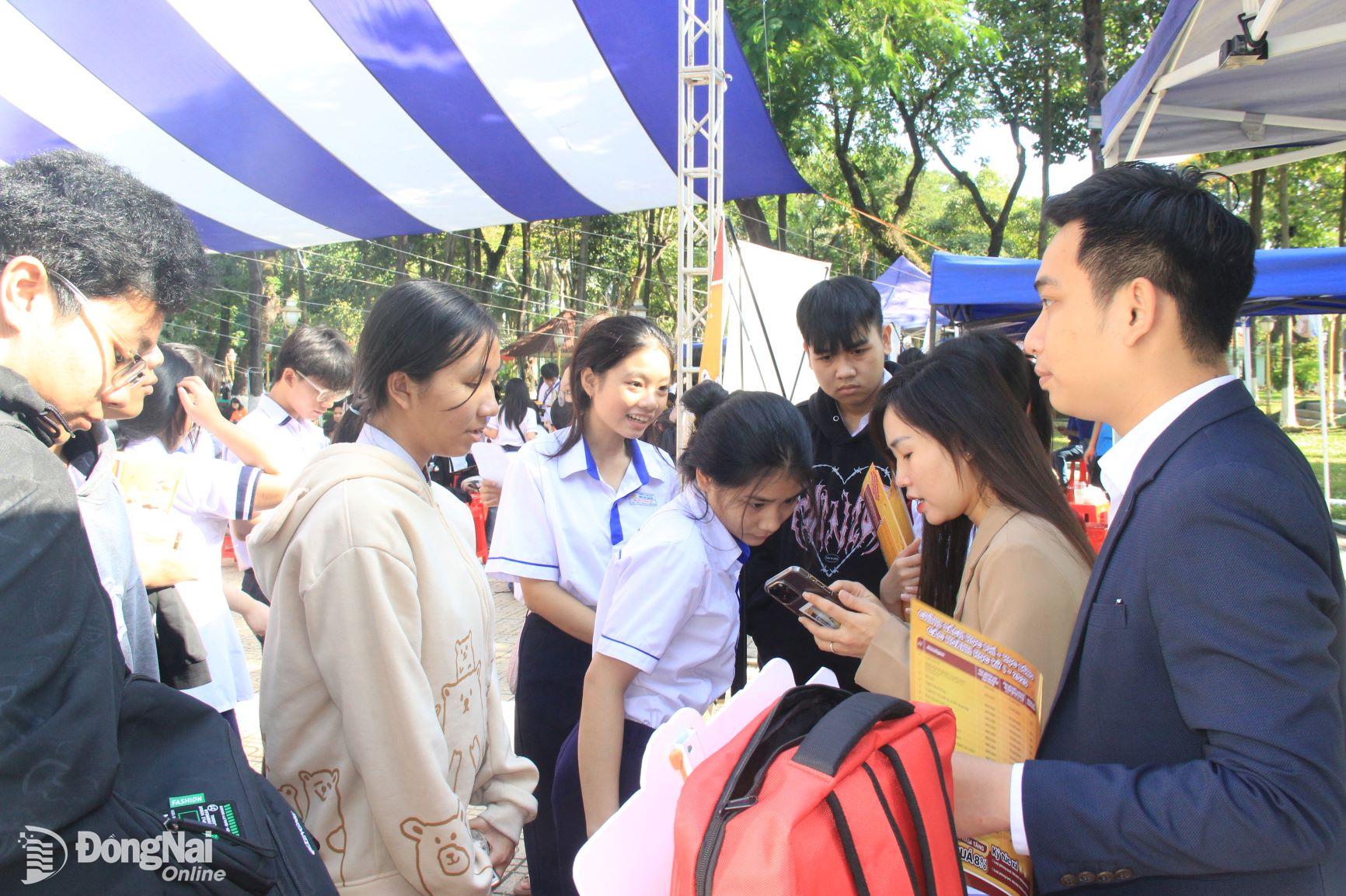 Học sinh chủ động tìm hiểu thông tin ngành nghề đào tạo của các trường đại học, cao đẳng tại các gian hàng. Ảnh: Nga Sơn

