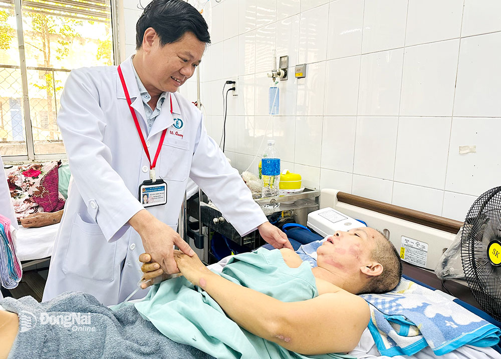 BS CKII Nguyễn Tường Quang, Phó giám đốc Bệnh viện Đa khoa Thống Nhất thăm khám, động viên bệnh nhân sau khi bệnh nhân qua cơn nguy kịch. Ảnh: H.Dung