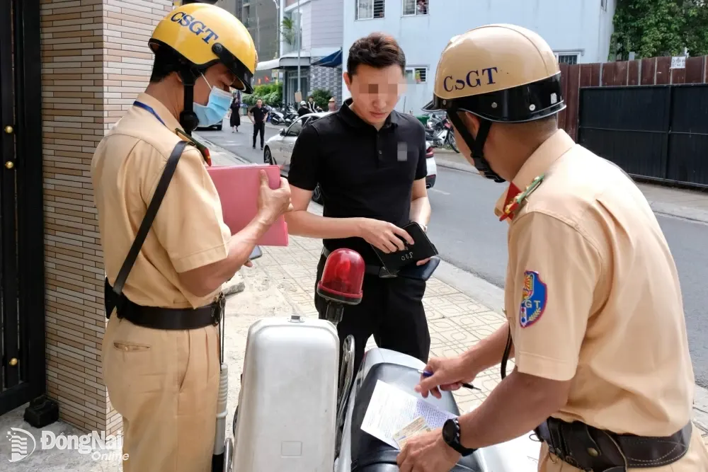 Lực lượng cảnh sát giao thông - trật tự kiểm tra giấy tờ một tài xế có xe ô tô đậu sai quy định. Ảnh: Đăng Tùng
