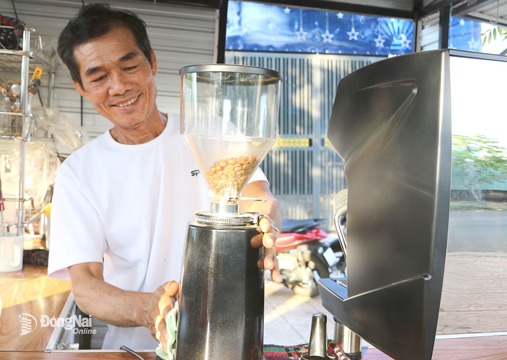 Ông Lý Sy Niềm (dân tộc Dao, P.Xuân Tân, TP.Long Khánh) bên máy pha cà phê bán giải khát trước nhà mình. Ảnh: V.Truyên
