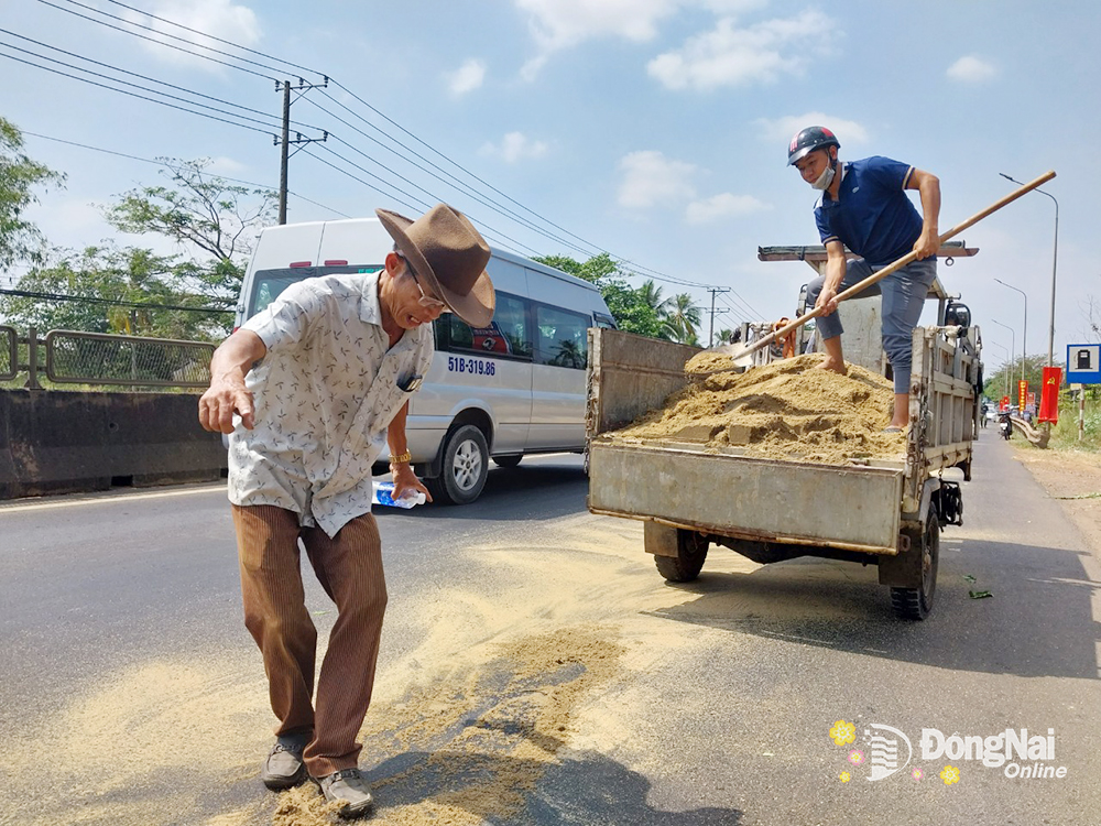 Công an xã Hưng Lộc cùng người dân hỗ trợ rãi cát lên bề mặt đường