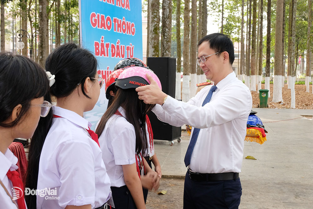 Phó chủ tịch UBND huyện Long Thành Lê Hoàng Sơn tặng mũ bảo hiểm cho học sinh Trường trung học cơ sở Nguyễn Đức Ứng (huyện Long Thành). Ảnh: Đăng Tùng