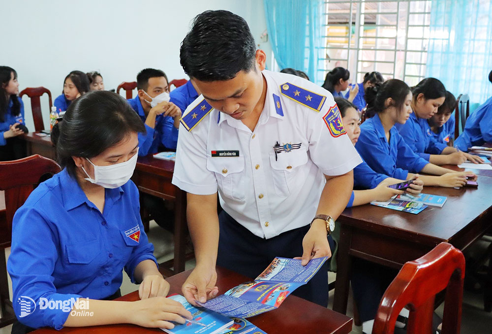 Cán bộ Đoàn Trinh sát số 2 phát tài liệu tuyên truyền về biển, đảo cho cán bộ, giáo viên tại huyện Nhơn Trạch. Ảnh: ĐVCC