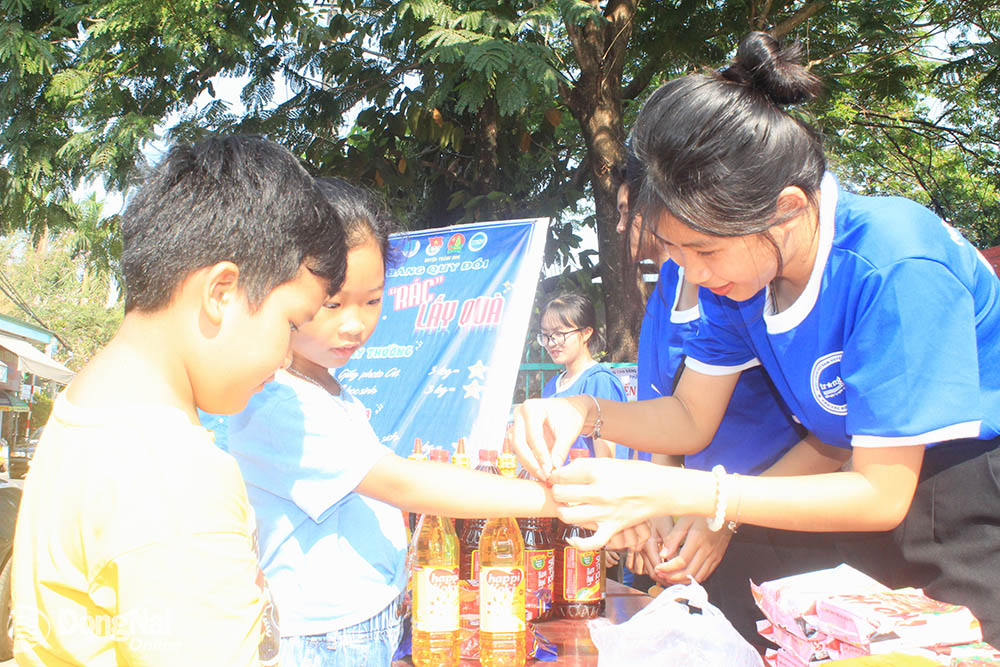 Đoàn viên, thanh niên huyện Trảng Bom hỗ trợ thiếu nhi lựa chọn quà tại gian hàng đổi rác thải lấy quà.Ảnh: Nga Sơn