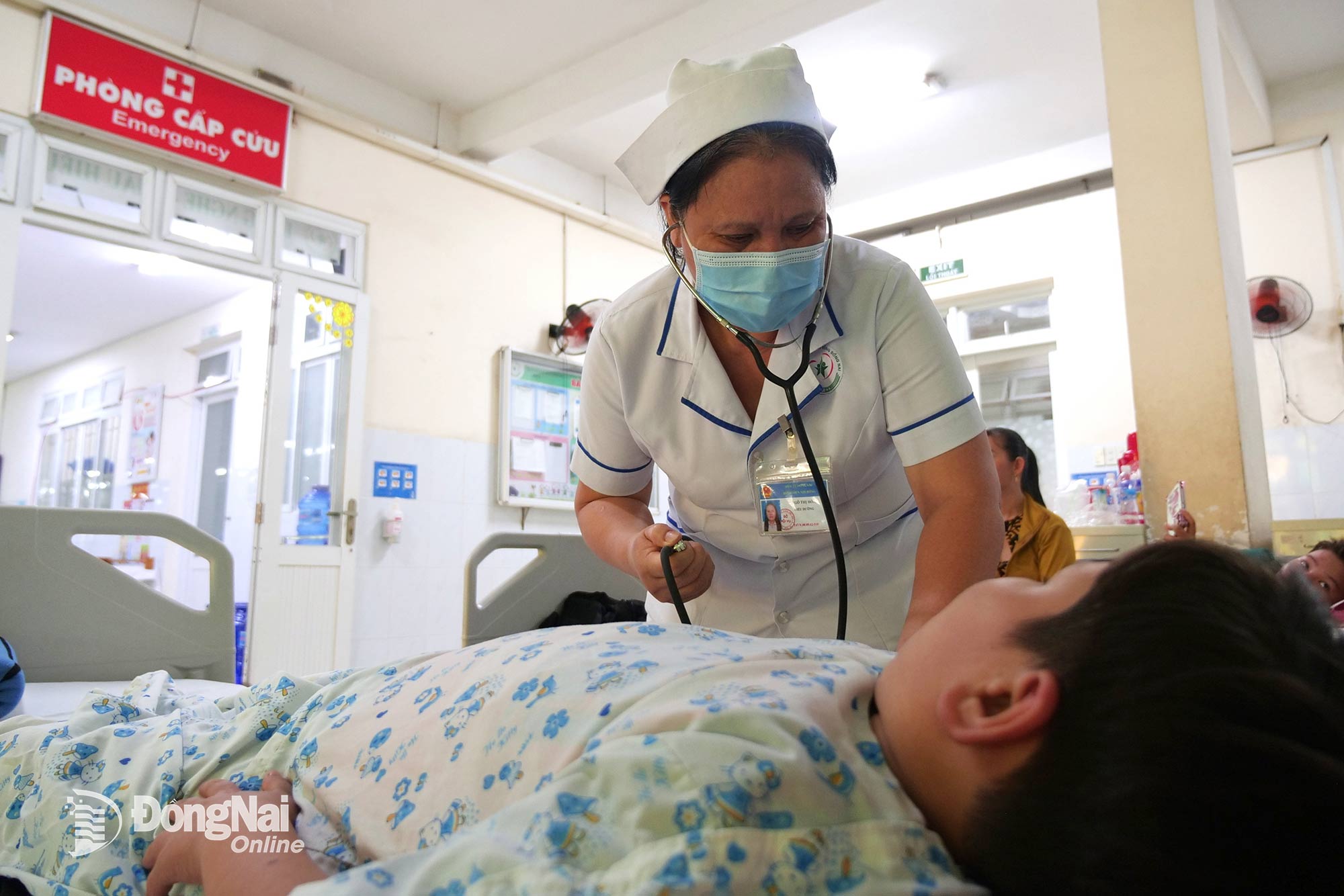 Điều dưỡng Ngô Thị Hòa kiểm tra huyết áp cho một bệnh nhi bị sốt xuất huyết điều trị tại Khoa Bệnh nhiệt đới, Bệnh viện Nhi đồng Đồng Nai. Ảnh: Hạnh Dung