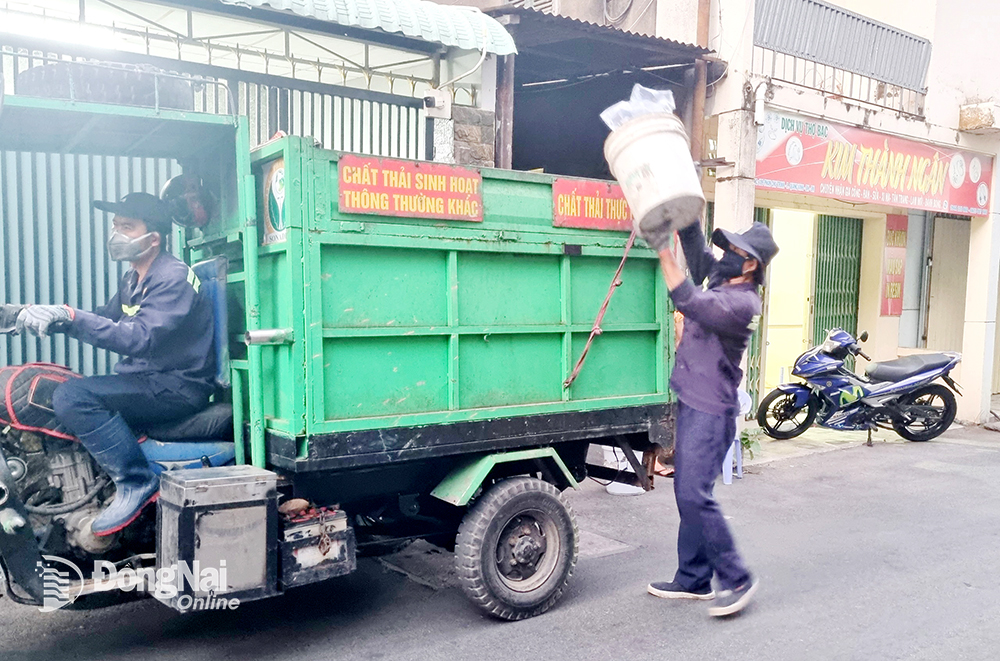 Công nhân vệ sinh môi trường thuộc Công ty CP Môi trường Sonadezi thu gom rác giữa thời tiết oi bức. Ảnh: L.Mai